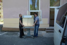Zdeněk a Michal nesou babybox do připraveného montážního rámu.