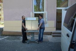 Zdeněk a Michal nesou babybox do připraveného montážního rámu. 